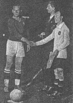 Przed meczem Wisła - Belgia wymieniono pamiątkowe proporczyki. Kpt. Reyman wręczył proporzec kapitanowi Belgii Hoydonrowi, pośrodku sędzia Langenas.